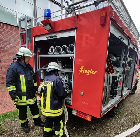 Ausbildende Lehrkraft und Truppmannanwärter am Feuerwehrfahrzeug 