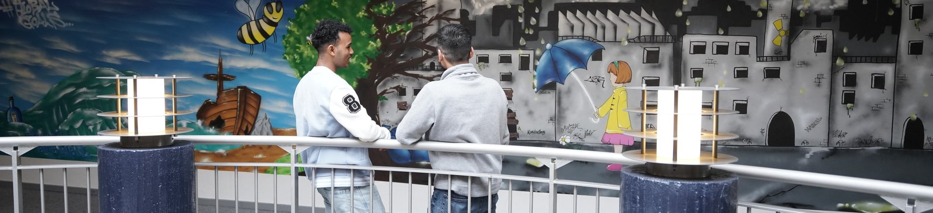 Schüler unterhalten sich vor einer bemalten Wand